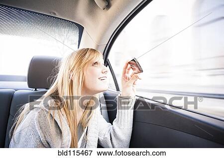 Stock Photo - Woman taking pictures out car window. Fotosearch