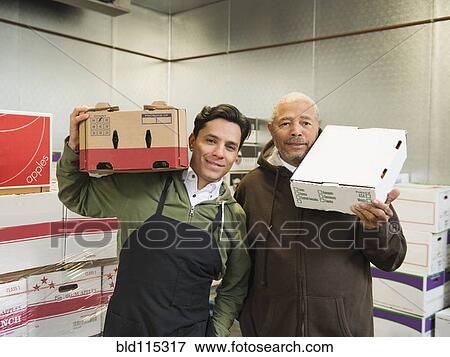 Stock Photo - Workers carrying boxes in walk-in freezer. Fotosearch