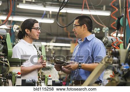 Stock Photo - Workers talking in textile factory. Fotosearch