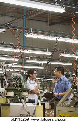 Stock Photo - Workers talking in textile factory. Fotosearch