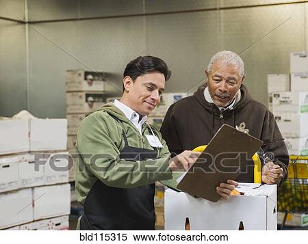 Stock Photography - Workers using clipboard in walk-in freezer. Fotosearch