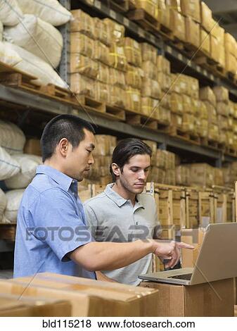 Stock Photo - Workers using laptop in textile factory. Fotosearch