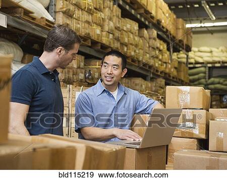 Stock Photo - Workers using laptop in textile factory. Fotosearch