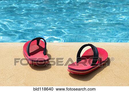 Stock Image - A pair of red flip flops at the swimming pool. Fotosearch