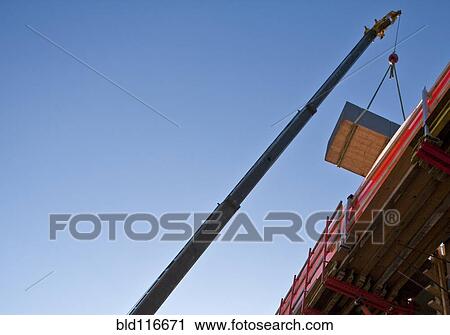Stock Image - Crane Moving Material at a Work Site. Fotosearch