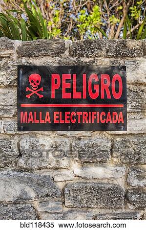 Stock Photography - Danger sign in Spanish on a stone wall in Cancun. Fotosearch