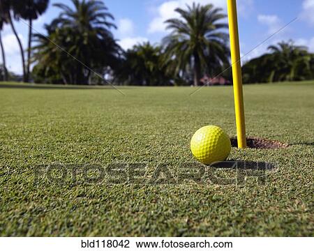 Stock Image - Golf Ball Lying Next to the Hole. Fotosearch