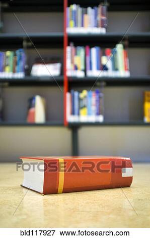 Stock Photo - Library book on the floor in front of a bookshelf. Fotosearch
