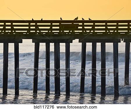 Stock Photograph - Pier by the Ocean at Sunrise. Fotosearch