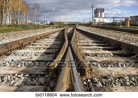 Railway tracks passing industrial storage buildings View Large Photo Image Picture - Railway tracks passing industrial storage buildings. Fotosearch