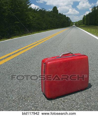Stock Image - Red Suitcase Abandoned in Road. Fotosearch