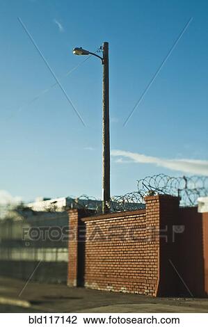 Street Lamp Behind Brick Wall With Concertina Wire View Large Photo Image Stock Image - Street Lamp Behind Brick Wall With Concertina Wire. Fotosearch