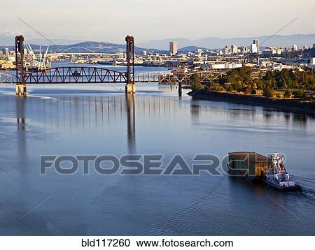 Stock Image - Tugboat Pushing Barge in River. Fotosearch