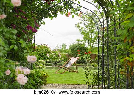 A country garden with a rose arch, and flowering climbing roses View Large Photo Image Stock Photo - A country garden with a rose arch, and flowering climbing roses. Fotosearch