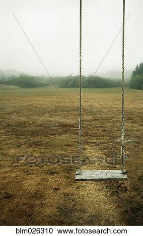 Stock Image - A empty children's' swing in a field. Fotosearch