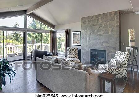 Stock Photography - A living room with hardwood floors, couch, upholstered chairs, and a fireplace. Fotosearch