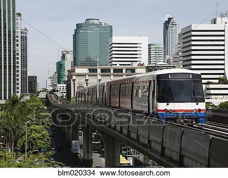 A mass transit train on an elevated track passes modern building View Large Photo Image Picture - A mass transit train on an elevated track passes modern building. Fotosearch