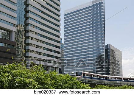 Stock Photo - A mass transit train on an elevated track passes modern building. Fotosearch