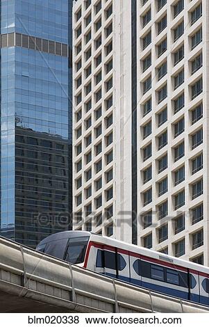 A mass transit train on an elevated track passes modern building View Large Photo Image Stock Photo - A mass transit train on an elevated track passes modern building. Fotosearch