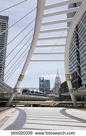 A mass transit train on an elevated track passes modern building View Large Photo Image Stock Photo - A mass transit train on an elevated track passes modern building. Fotosearch