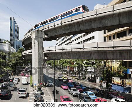 Stock Photography - A mass transit train on an elevated track passes modern building. Fotosearch