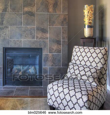 Stock Photograph - A tiled fireplace and chair in a living room. Fotosearch