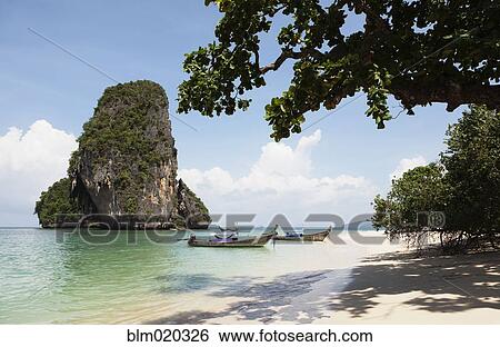 A traditional long tail boat moored in shallow water on Tham Phra Nang beach View Large Photo Image Stock Photograph - A traditional long tail boat moored in shallow water on Tham Phra Nang beach. Fotosearch