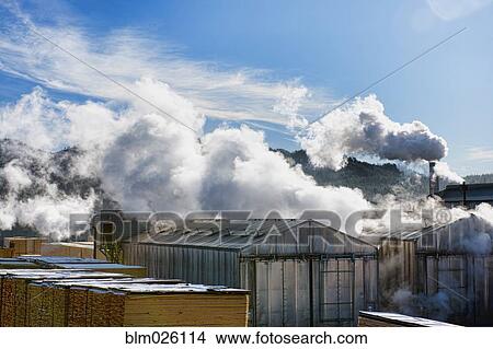 Picture - A working saw mil, steam and vapor escaping from chimneys. Fotosearch