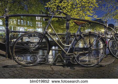 Stock Image - Bicycles Secured to Canal Railing. Fotosearch