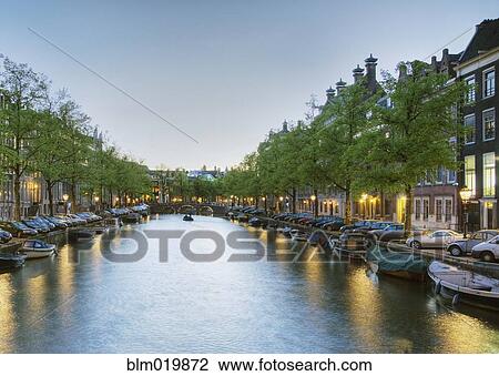 Stock Image - Boats in a Tree Lined Canal at Dusk. Fotosearch