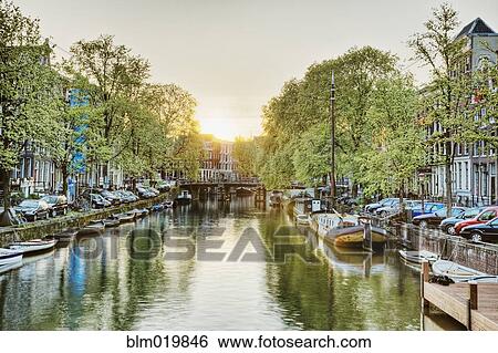 Stock Photograph - Boats Moored in a Tree Lined Canal at Daybreak. Fotosearch