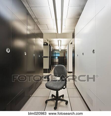 Stock Image - Chair in an Aisle in Between Electronics Cabinets. Fotosearch