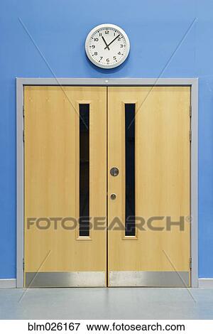 Clock above double doors in the main hall of a secondary school View Large Photo Image Stock Photo - Clock above double doors in the main hall of a secondary school. Fotosearch