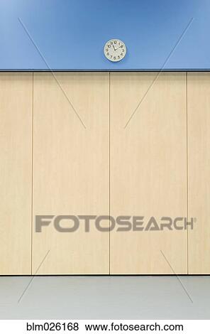 Stock Photo - Clock on a blue wall in the main hall of a secondary school. Fotosearch
