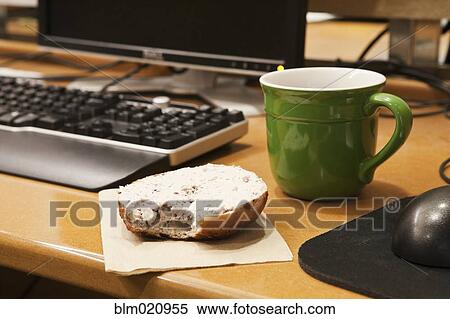 Stock Photography - Coffee Cup and Bagel on a Desk. Fotosearch