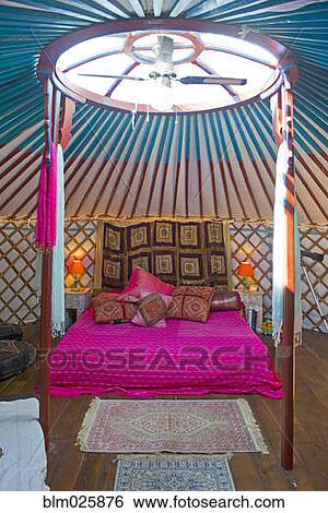 Stock Photograph - King size bed in a Mongolian yurt with skylight and fan. Fotosearch