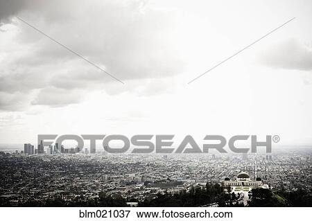Stock Photo - Los Angeles Skyline and Griffith Observatory Beneath Cloudy Sky. Fotosearch
