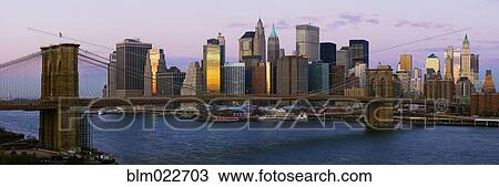 Stock Image - Lower Manhattan Skyline and Brooklyn Bridge at Dawn. Fotosearch