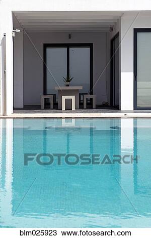 Minimalist architecture, a modern mansion reflected in the gentle ripples of an infinity pool View Large Photo Image Stock Image - Minimalist architecture, a modern mansion reflected in the gentle ripples of an infinity pool. Fotosearch
