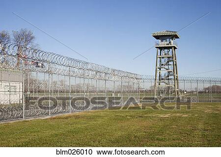 Stock Image - Prison fence, locked gate and barbed wire at Correctional Facility. Fotosearch