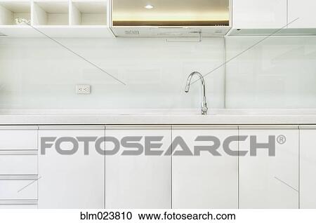 Stock Image - Silver arched mixer tap and sink in white modern kitchen. Fotosearch