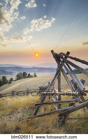Stock Image - Strong log stock fence in ranch lands, over the mountains and valleys of Montana. Fotosearch