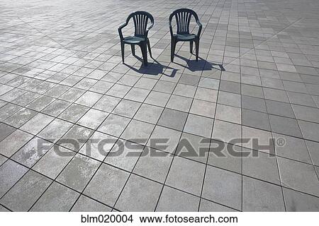 Picture - Tiled patio space with two plastic garden chairs. Fotosearch