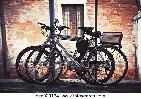 Two bikes resting against some poles in Venice, Italy View Large Photo Image Picture - Two bikes resting against some poles in Venice, Italy. Fotosearch