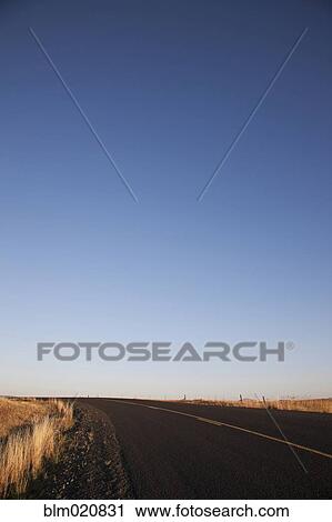 Stock Image - Two Lane Road Between Fields. Fotosearch