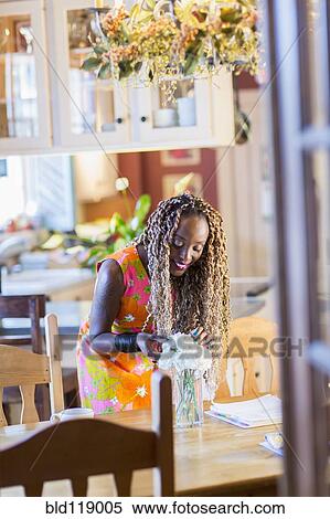 Stock Photography - African American woman arranging bouquet of flowers. Fotosearch