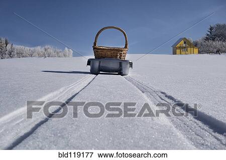 Stock Photo - Basket on sled making tire tracks in snowy landscape. Fotosearch