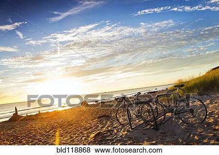 Stock Photo - Bicycles parked on beach at sunset. Fotosearch