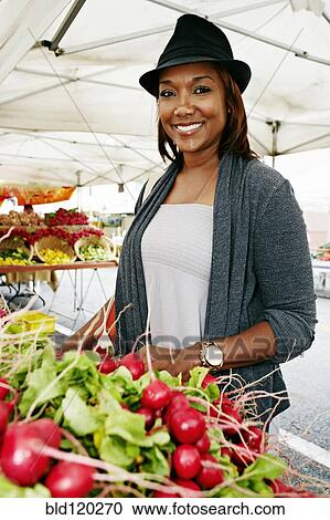 Stock Image - Black woman shopping at outdoor market. Fotosearch