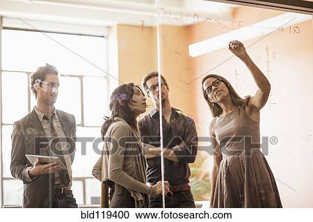 Stock Image - Business people writing on glass wall. Fotosearch